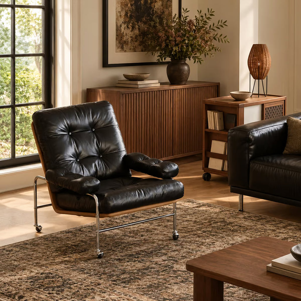 Black leather lounge chair beside a window in a living room, with a wood sideboard and rug