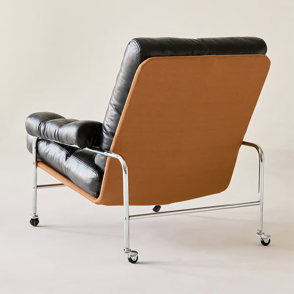 Black leather lounge chair from behind, showing the caramel outer shell and stainless steel frame