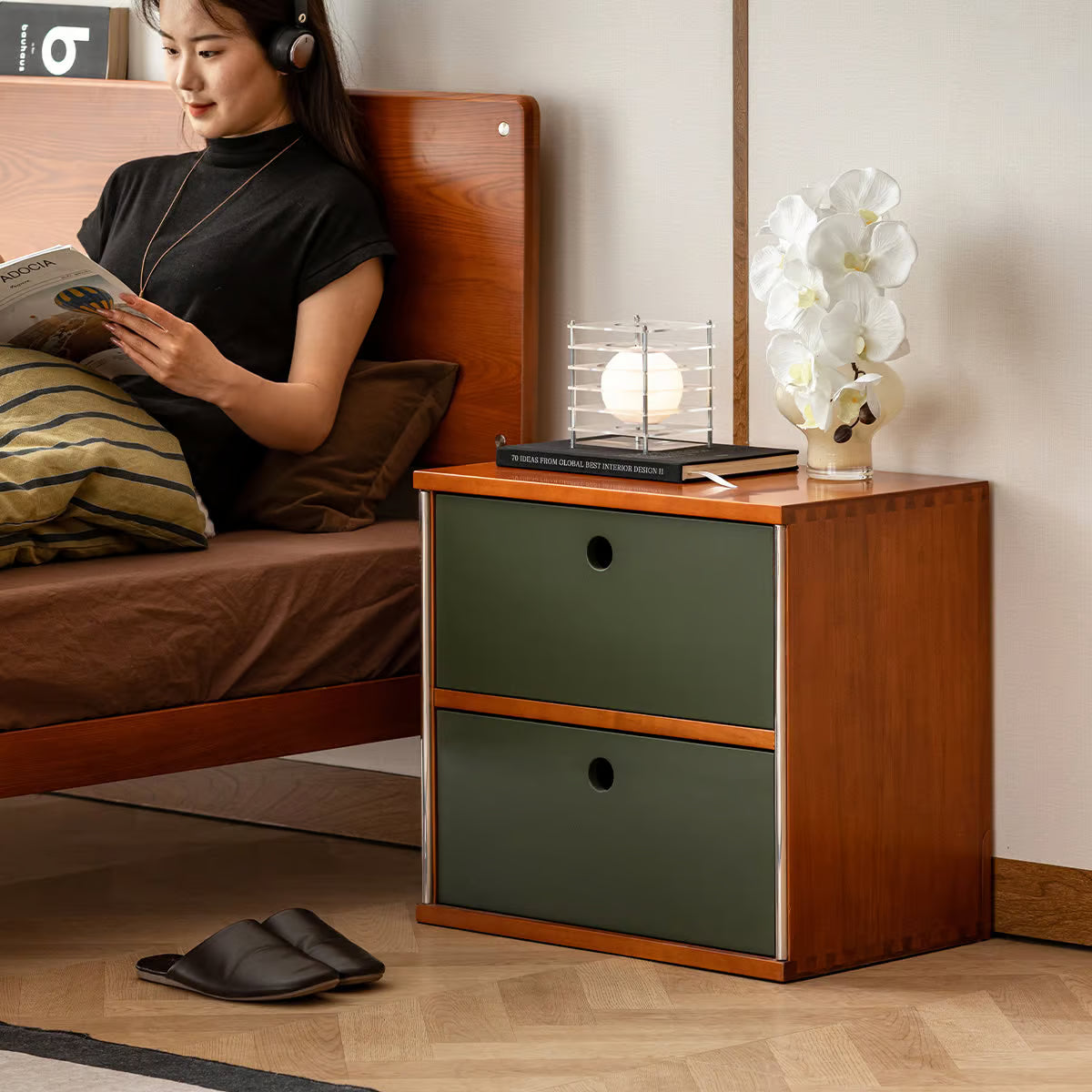 Green two drawer storage cube used as a bedside nightstand next to a wood bed frame