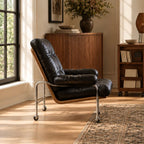 Leather reading chair set by the window on its casters, facing a sideboard and bookshelf