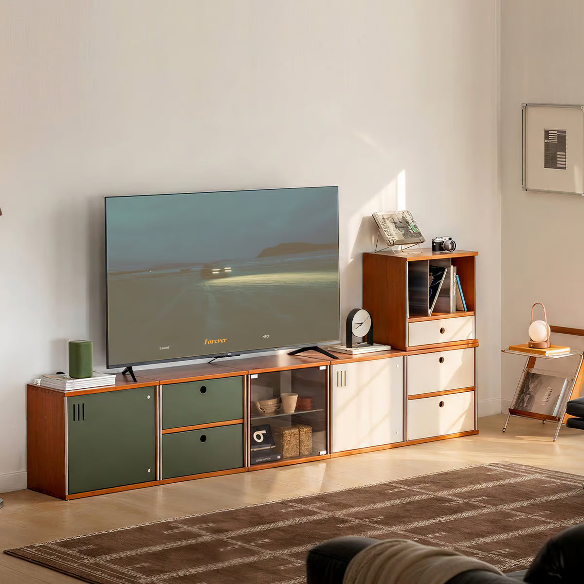Modular TV stand built from four stacked storage cubes in green and cream with a flat screen TV on top