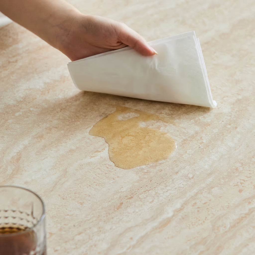 Spilled liquid being wiped off the sintered stone table top with a dry tissue