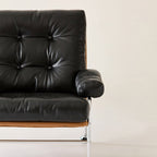 Top grain leather chair seen close up from the front, with the padded arm and tufted back