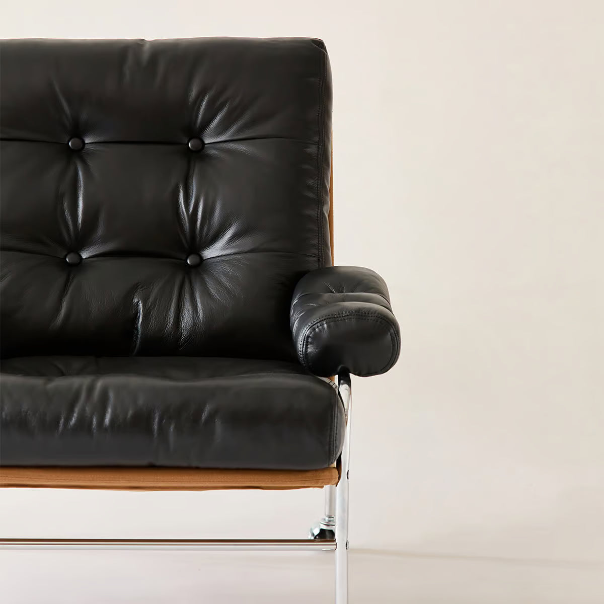 Top grain leather chair seen close up from the front, with the padded arm and tufted back